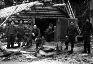 Ouvriers devant un camp en bois rond