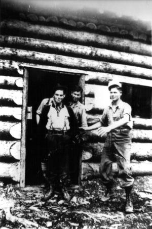 Trois travailleurs dans un camp en bois rond