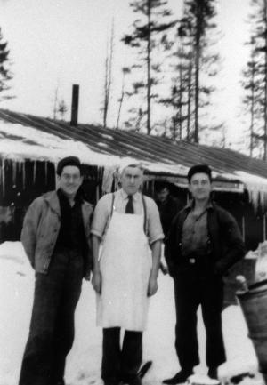Trois travailleurs forestiers devant  un camp