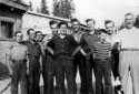 M. Fred Pettigrew et ses hommes devant un camp fait de planches